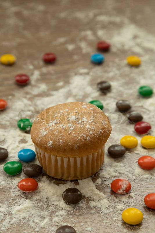 muffin with various colored chocolates, dusted with sugar, delicious desserts