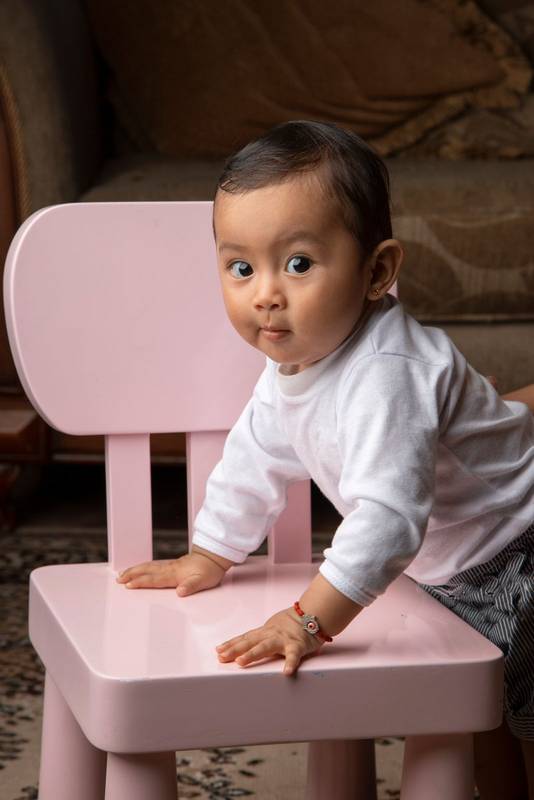 cute and adorable little latin girl cuddled up on a pink chair