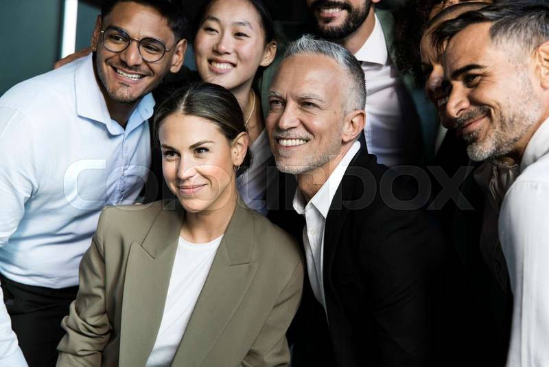 Multiracial group of successful business people taking a selfie outside. Diverse office colleagues taking a picture together smiling.