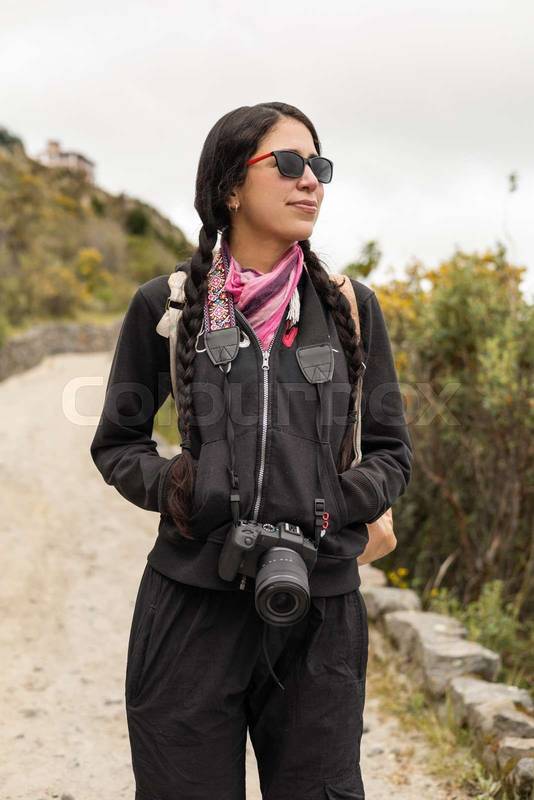 woman walks along a peaceful dirt trail with her hands in pockets, feeling the cool air