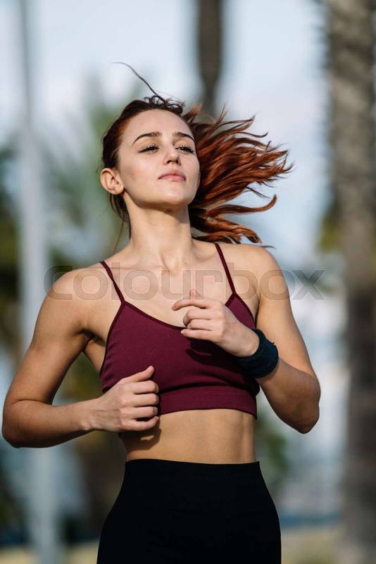 Sports female running outdoors in sportswear. Beautiful woman working out outside doing fitness exercises.