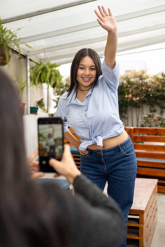 smartphone taking a photo of a cheerful woman posing outdoors, highlighting the connection between modern technology and joyful moments