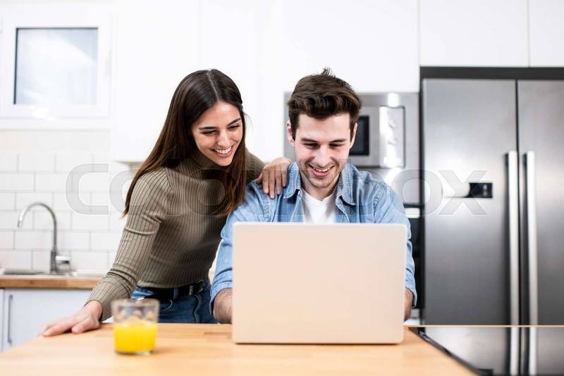 Young couple working together with a laptop at home - Smiling caucasian man and woman looking at computer