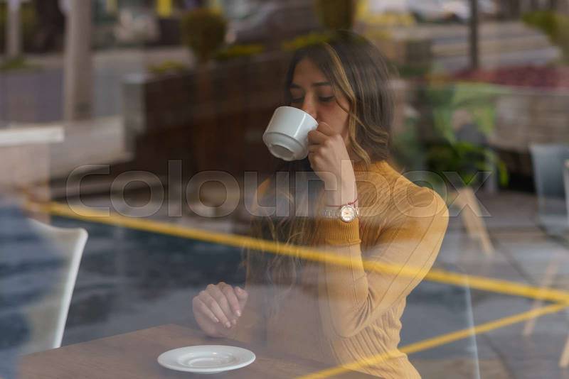 coffee shop interior a young woman with long hair having a cup of coffee as breakfast,