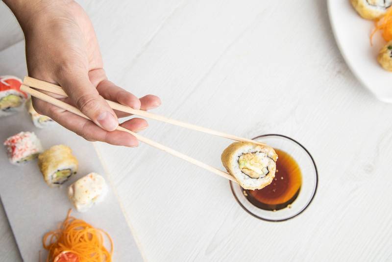 restaurant sushi roll with wooden chopsticks, at the bottom is a container with sauce