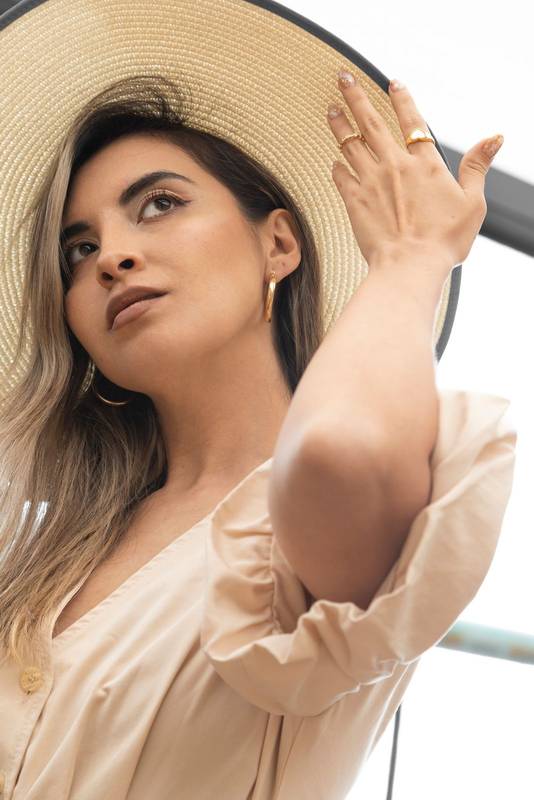 woman with long hair with natural makeup, wears a straw hat, rings and earrings, delicate jewelry