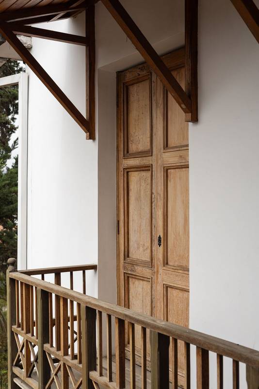 antique wooden door opens to a bright balcony of a stylish old house