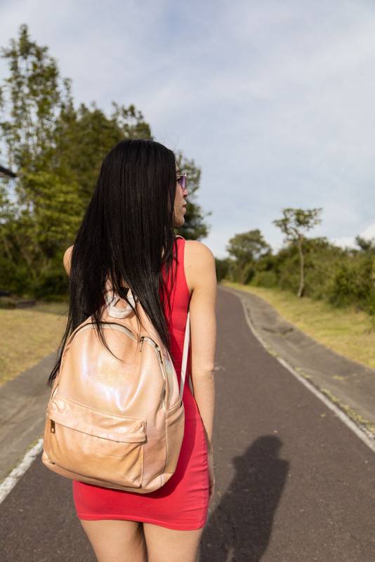 walking on asphalt road, wearing red casual dress and backpack, tourist