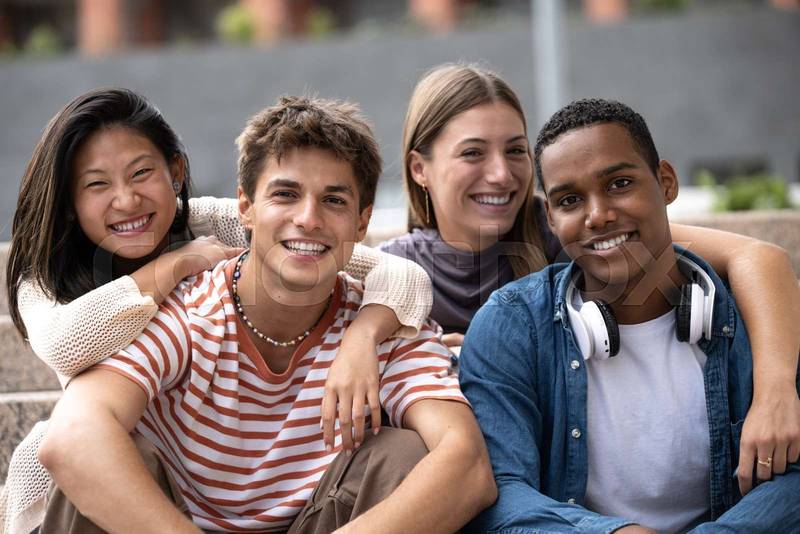 Beautiful young millennials smiling looking at camera.Group of friends sitting together happy and carefree in the street.