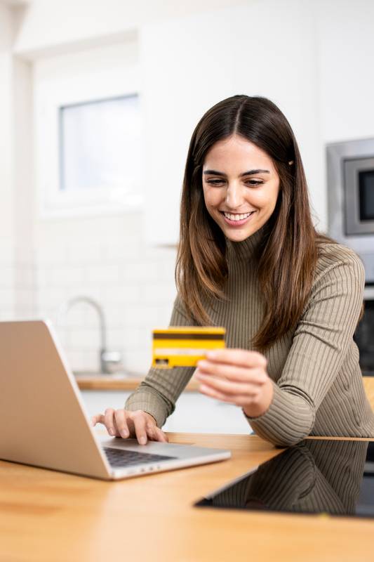 happy young attractive woman shopping online with a laptop computer using a credit card. e-commerce, business concept