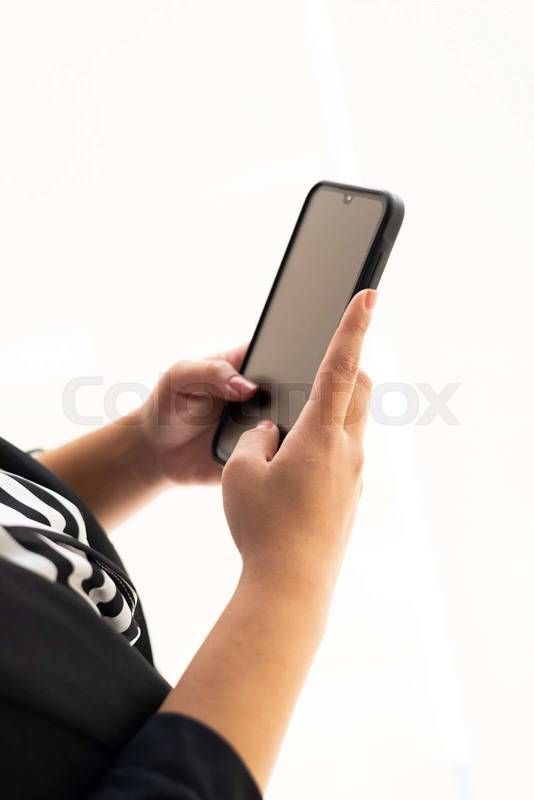 hands typing on a smartphone in an office setting. The image emphasizes communication, technology