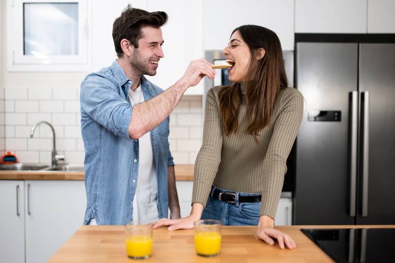 Happy young couple preparing healthy food on the kitchen. Romantic and funny breakfast