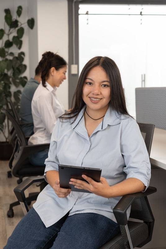 woman works on her tablet while seated on a swivel chair, working on a office