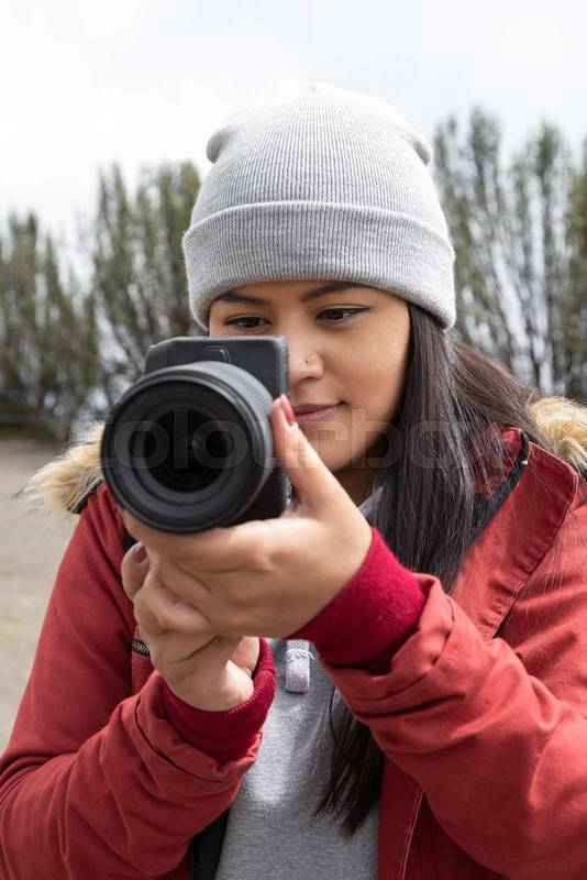 lens of a modern camera held by a woman
