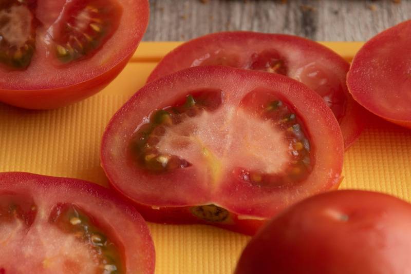 fresh tomato slices with its seeds on a chopping board, vegetable