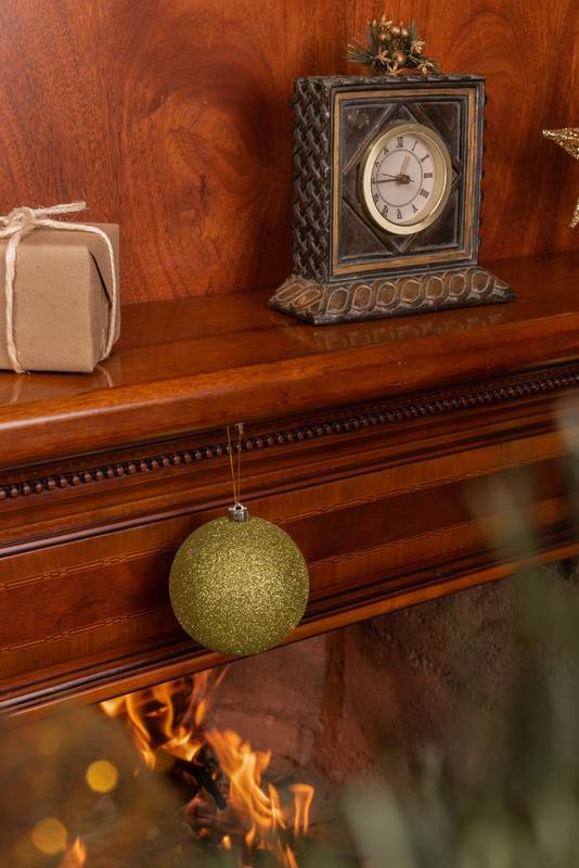 interior design, branches of an artificial christmas tree with colorful bulbs and a lit wooden fireplace