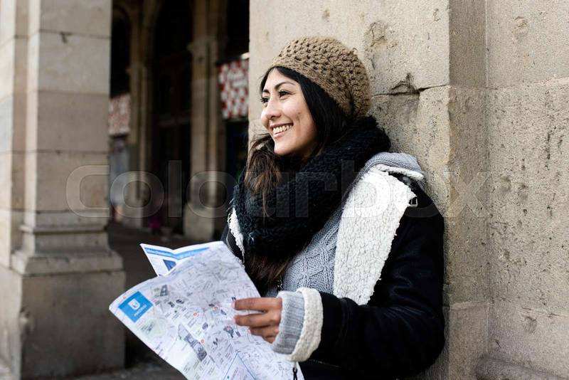 young tourist woman exploring city map in the street. holidays, tourism and travel concept