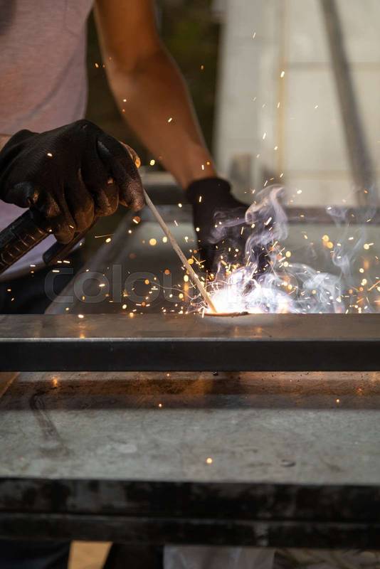 wearing protective gloves while using a metal welding tool, sparks from the machine