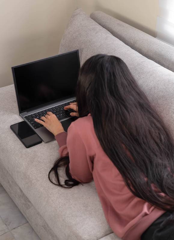 holding her laptop and browsing, enjoying a quiet, relaxed moment in a comfortable and cozy domestic setting