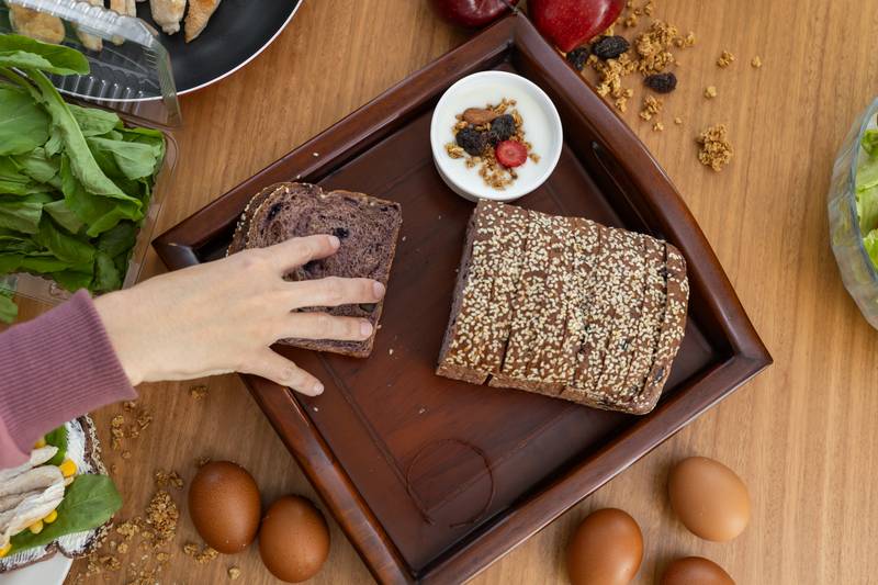hand delicately taking a slice of soft, fresh bread, table with food