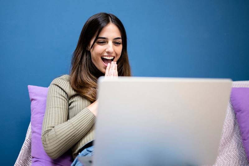 excited beautiful woman looking at laptop - happy laughing girl reading an email