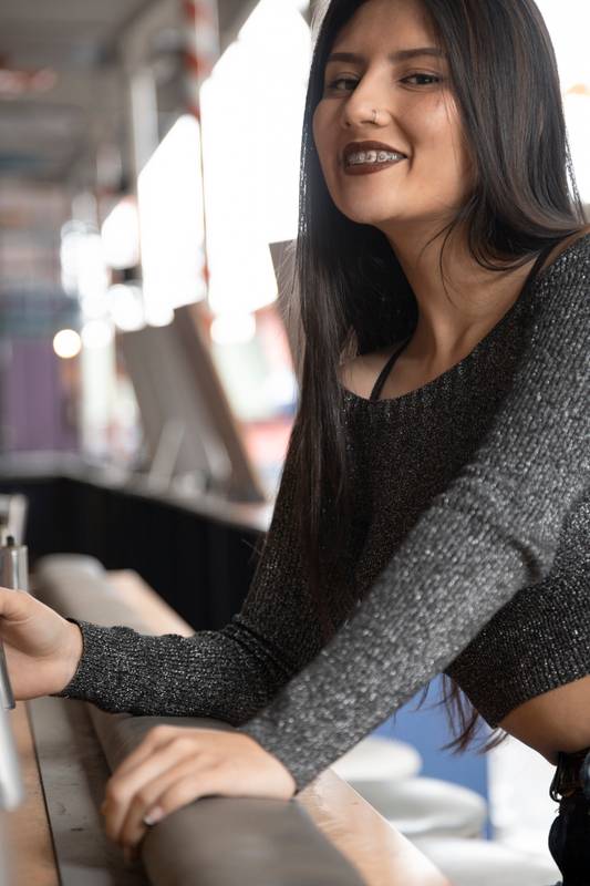 beautiful cheerful Latin woman leaning against a bar