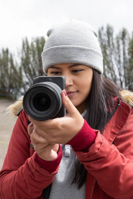 lens of a modern camera held by a woman