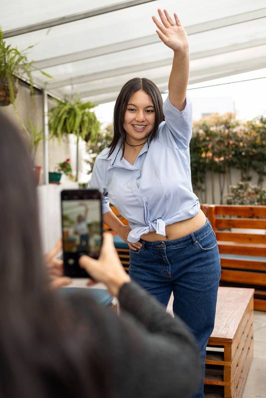 smartphone taking a photo of a cheerful woman posing outdoors, highlighting the connection between modern technology and joyful moments