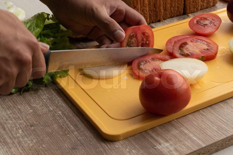hand of a person with a knife cutting fresh vegetables