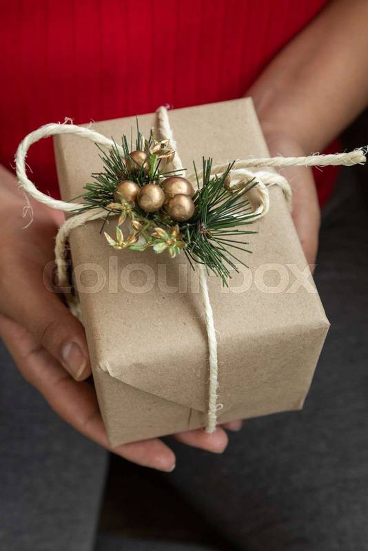 person's hands holding a gift decorated with a ribbon, Christmas ornament