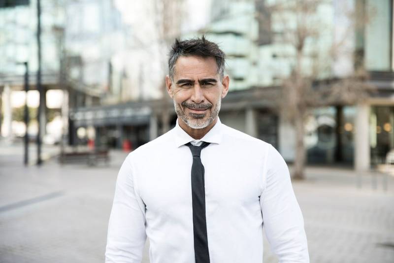 Portrait of a handsome mature CEO smiling with an urban background in a casual style. Attractive senior businessman looking at camera with a confident smile.
