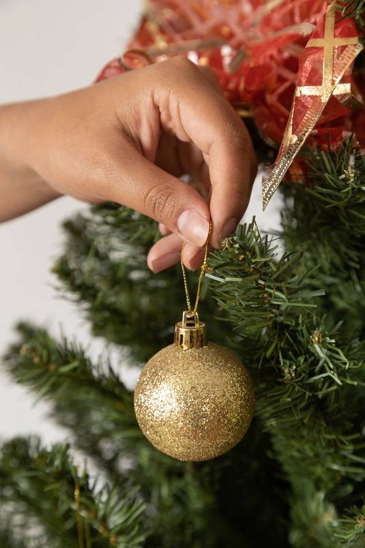 hanging a light bulb on the branch of an artificial christmas tree, decoration