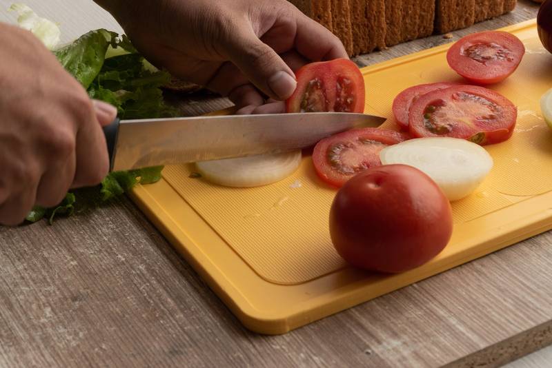 hand of a person with a knife cutting fresh vegetables