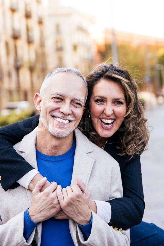 Affectionate mid adult woman hugging handsome man having fun together in a romantic date. Lovely mature couple bonding together .