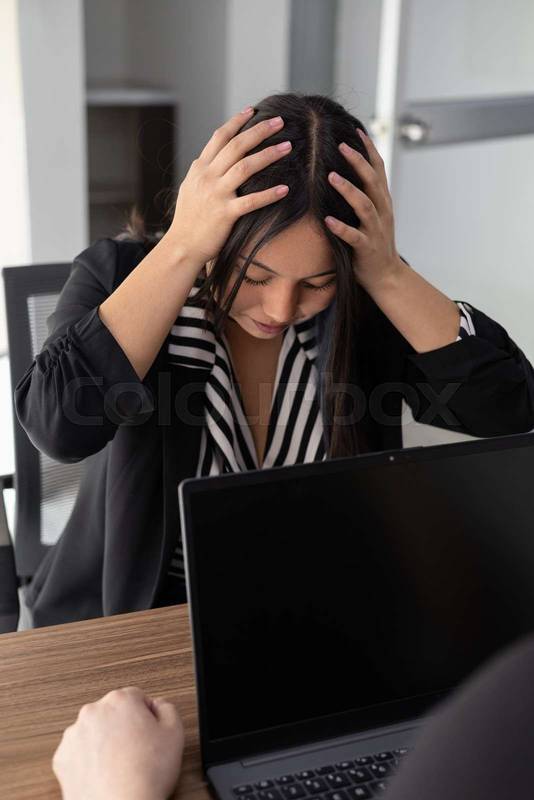 young professional faces intense pressure, head in hands, as workplace stress