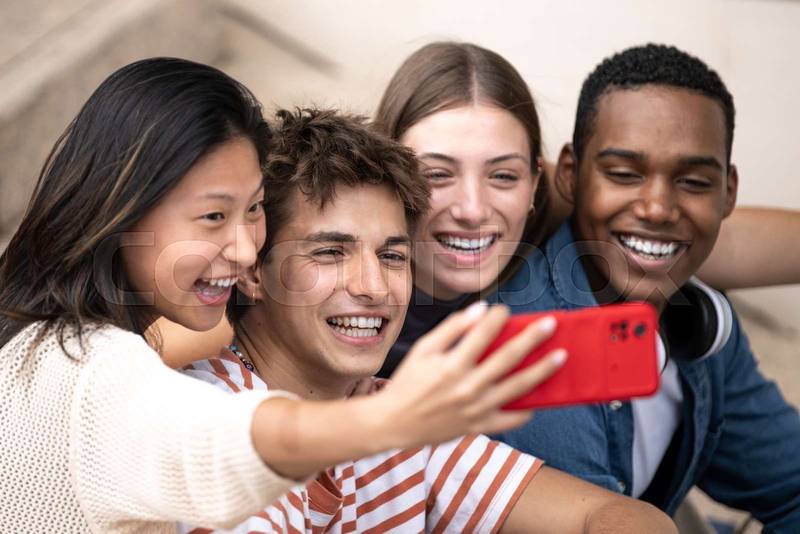 Multiracial group of friends taking a selfie outside.Young beautiful people taking a picture smiling and sitting in stairs.