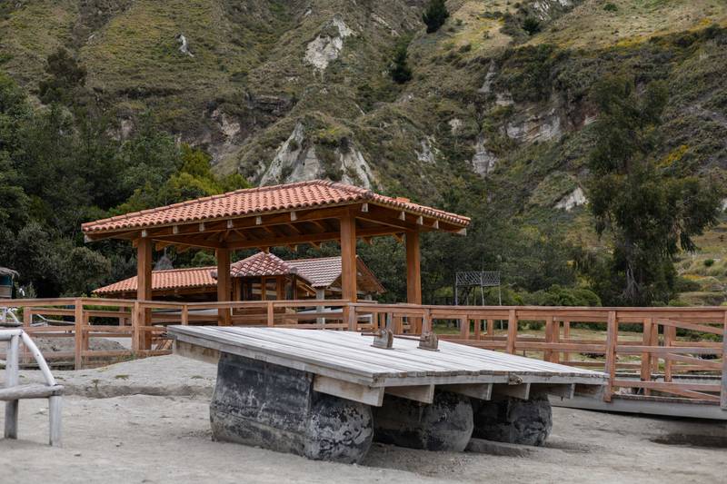 charming cabin stands behind a rustic stone picnic table surrounded by lush greenery