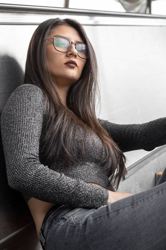 details of young latin woman with straight black hair wears glasses, jeans