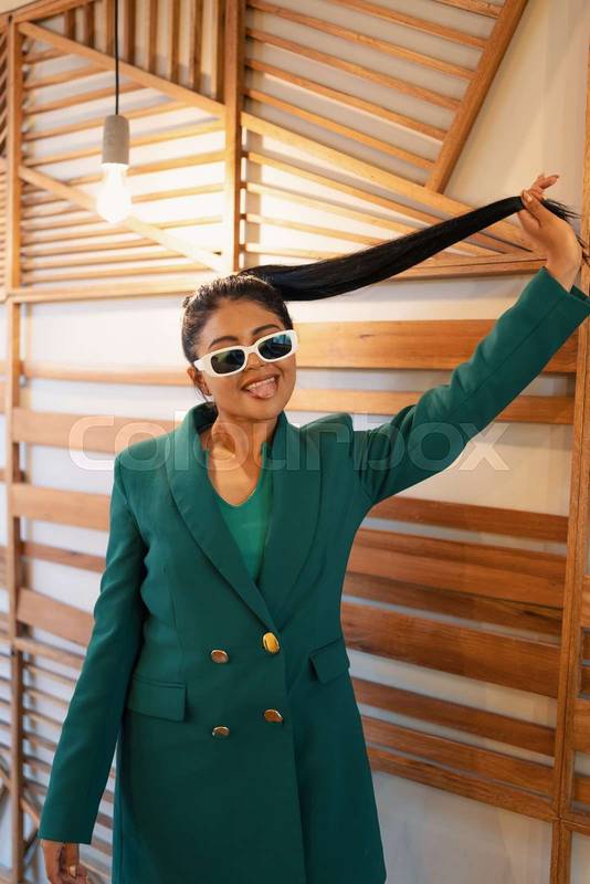 having fun playing with her hair styled in a ponytail, young latin woman