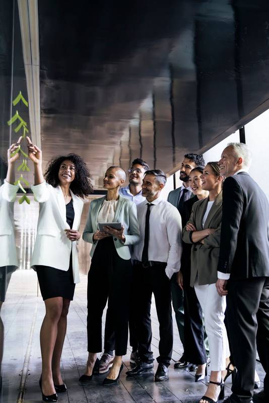 Multiracial group of businesspeople having a meeting standing in an office corridor. Young female executive explaining and talking in a casual meeting with diverse colleagues