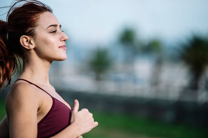Close up of active sport fitness woman jogging outside. Female young adult athlete running training cardio for a marathon.