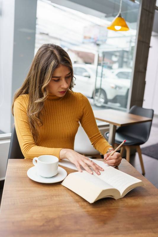 writing on a book with a pencil a beautiful young latin woman