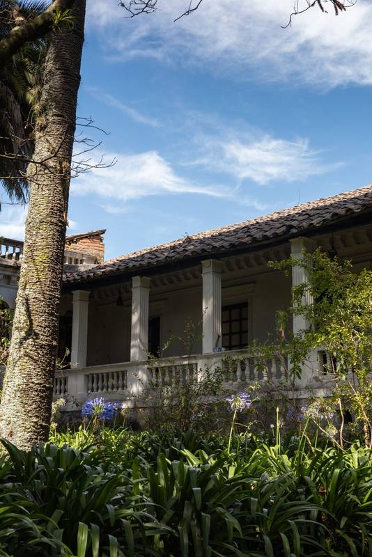 featuring clay tile roof, white colonial columns, and rustic charm