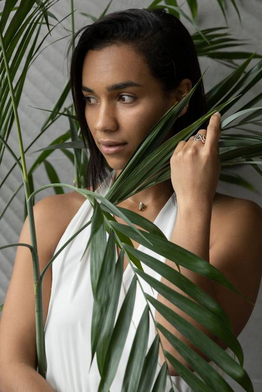 brunette woman, around are leaves of a plant