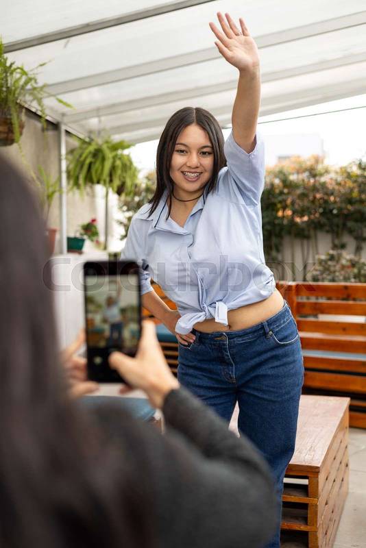 smartphone taking a photo of a cheerful woman posing outdoors, highlighting the connection between modern technology and joyful moments
