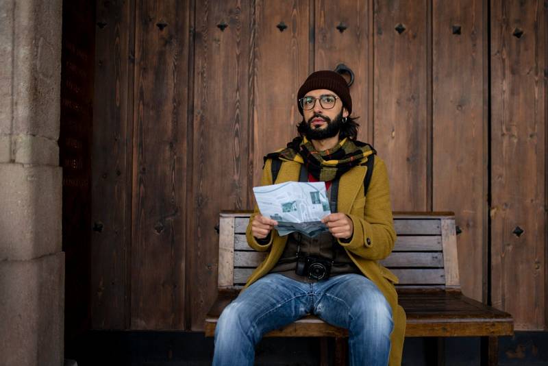 young tourist woman exploring city map in the street. holidays, tourism and travel concept