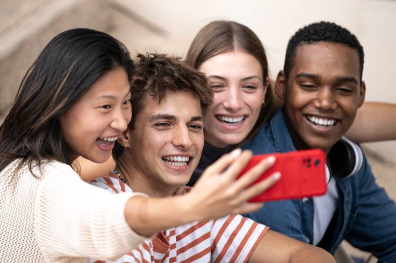 Multiracial group of friends taking a selfie outside.Young beautiful people taking a picture smiling and sitting in stairs.