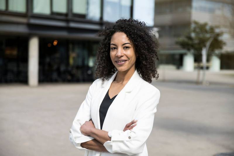 Portrait of smiling young businesswoman standing with her arms crossed and looking at camera. Successful woman finance professional woman. Business concept.