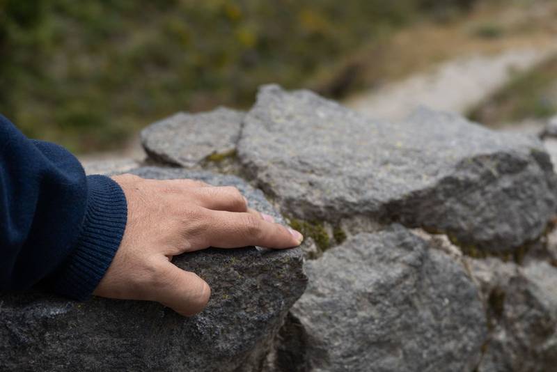 hand gently placed on textured rocks. The image conveys themes of grounding, connection to nature