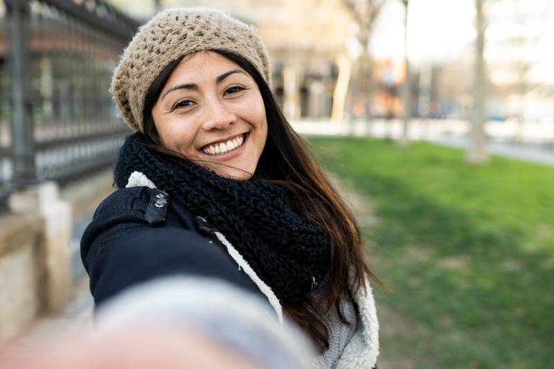 happy woman making a selfie showing two finger in the city. Cheerful portrait of a young female tourist. Holidays, people concept